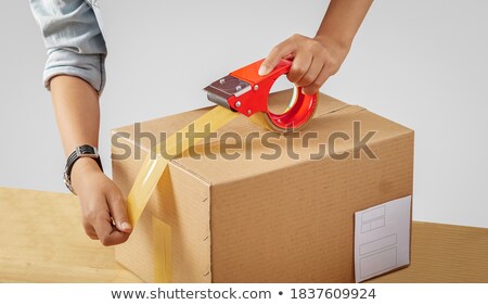 Foto d'archivio: Warehouse Worker Packing Parcel With Scotch Tape