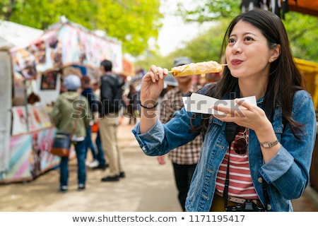 Stockfoto: Happy Cute Gilr Eating Street Food And Looking Enjoyable In A Traditional Small Fair