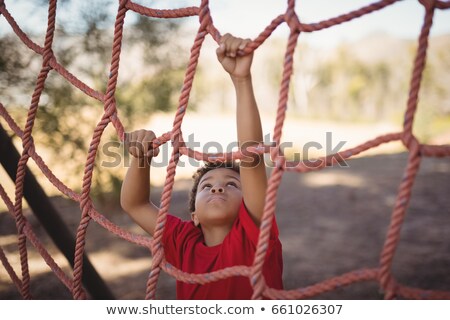 Foto d'archivio: Boy Climbing A Net During Obstacle Course Training