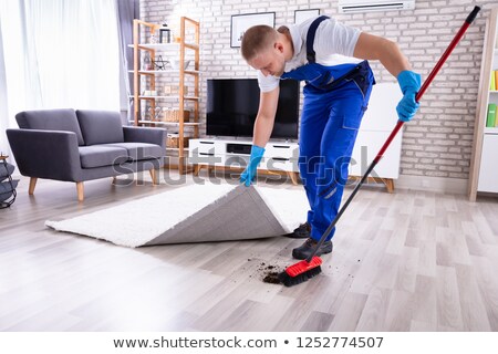 Foto stock: Janitor Removing Dirt Under The Carpet