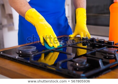 Stock photo: Man With Rag Cleaning Cooker At Home Kitchen