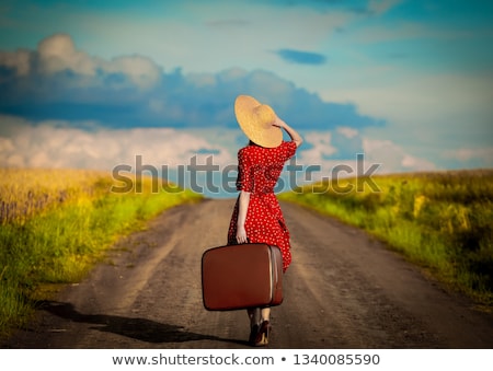 Stockfoto: Young Woman With A Yellow Suitcase Is Traveling On The Road Hitc