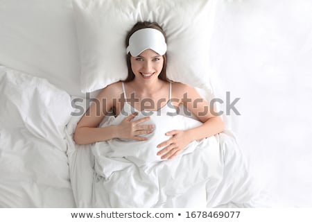 Foto stock: Happy Young Woman With Pillow Lying In Bed At Home