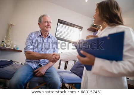 Foto stock: Doctor Shaking Hand Of Patient In Hospital Bed