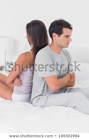 Foto stock: Couple Ignoring Each Other Sitting Back To Back On Bed