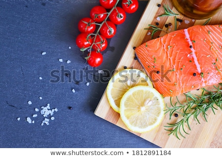 Stock fotó: Fresh Raw Salmon Slice On Chopping Board With Oil Tomatoes And Lemon On Stone Kitchen Table Backgrou