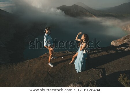 ストックフォト: Young Tourist Man And Woman Stand At The Edge Of The Crater Of The Ijen Volcano Or Kawah Ijen On The