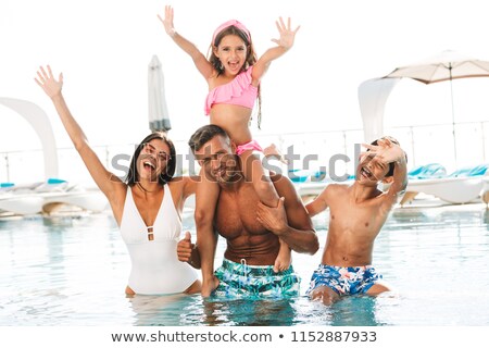 Stockfoto: Excited Young Family Having Fun Inside A Swimming Pool