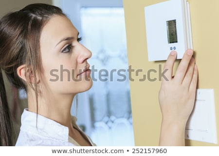 Stock photo: Woman Set The Thermostat At Home