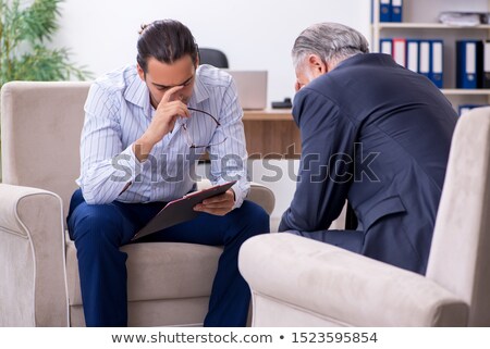 Foto stock: Old Man Visiting Young Male Doctor