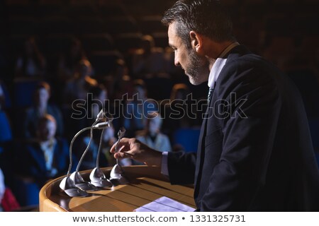 Foto d'archivio: Side View Of Caucasian Businessman Holding Podium Speaker In His Hand At Auditorium