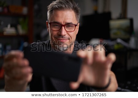 Сток-фото: Smiling Man In Armchair Taking Selfie