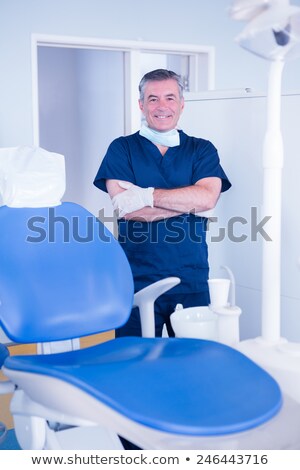 Сток-фото: Dentist In Blue Scrubs Smiling At Camera Beside Chair