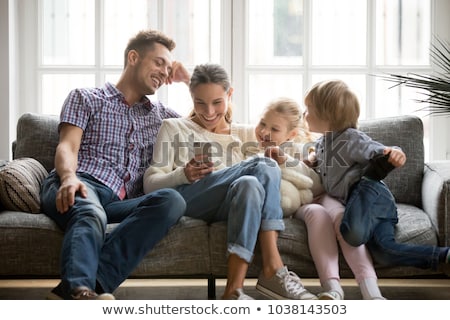 Foto stock: Couple Using Mobile Phone In Living Room At Home