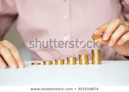 Foto stock: Female Hand Stacking Gold Coins Into Increasing Columns