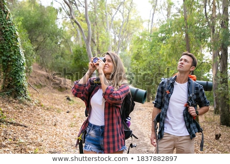 Foto d'archivio: Pretty Ladies Friends Walking Outdoors With Backpacks Take A Photo By Mobile Phone