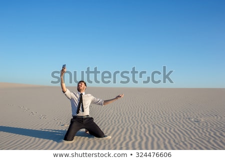 [[stock_photo]]: Poor Signal Businessman Searching For Mobile Phone Signal In Desert