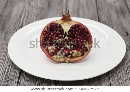 Stock foto: Pomegranates Have Broken Into Pieces With Red Berries On A Porcelain Plate On A Dark Background