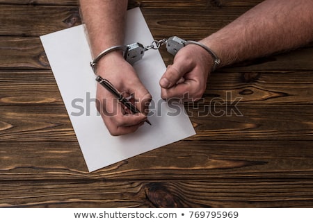 Stockfoto: Male Hands Cuffed Signing Confession Top View
