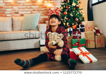 [[stock_photo]]: Girl In Red Dress Hugging Teddy Bear At Home