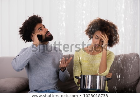 [[stock_photo]]: Man Collecting Water Leakage In Bucket While Calling Plumber