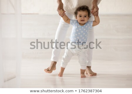 ストックフォト: Parent Help Baby Daughter Take First Steps At Home