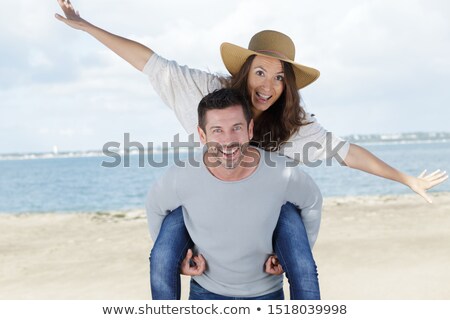 Stock photo: Couple Piggy Back Against Blurry Beach