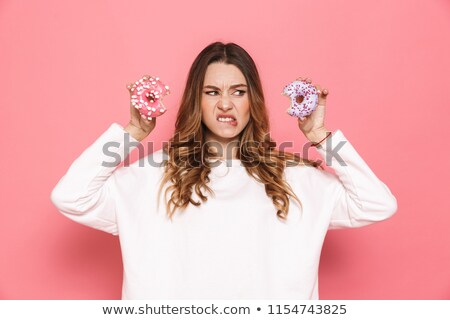 Stok fotoğraf: Portrait Of A Puzzled Young Woman Showing Donuts