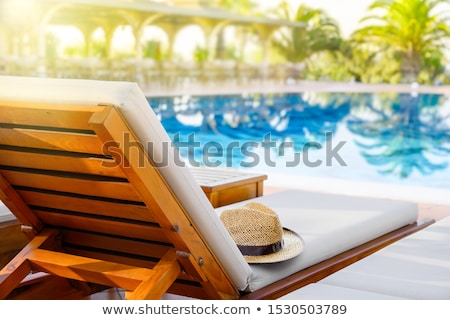 Сток-фото: Straw Hat On Deck Chair By The Swimming Pool