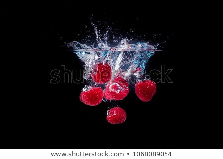 Foto stock: Raspberries Falling In Water On A Black Background
