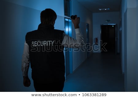 Сток-фото: Security Guard With Flashlight In Building Corridor