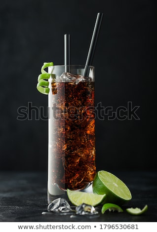 Stockfoto: Cuba Libre Cocktail In Highball Glass With Ice And Lime Peel On Bamboo Stick With Straw And Fresh Li