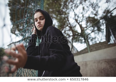 Stock fotó: Portrait Of Anxious Teenage Girl Leaning On Wire Mesh Fence At School Campus