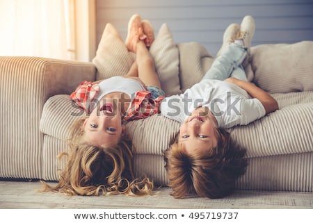 ストックフォト: Pretty Little Girl And Boy Are Lying On Their Backs On Sofa