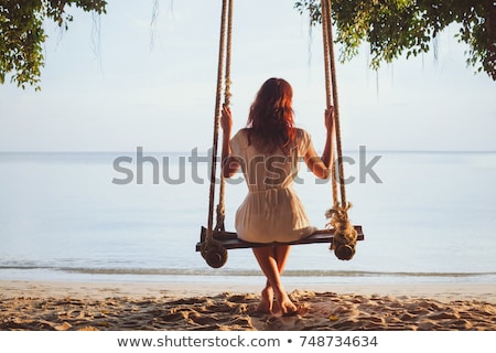 Foto d'archivio: Vacation Concept Happy Young Woman Sitting On Swing Enjoying Sea View