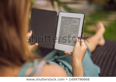 Stock foto: Woman Reads E Book On Deck Chair In The Garden