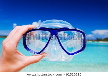 Foto stock: Hand Holding Snorkel Goggles Against Beach And Sky