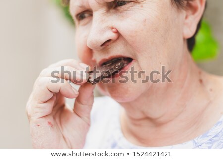 Portrait Of Cheerful Elderly Lady Eating Chocolate Looking At C Imagine de stoc © Madrolly