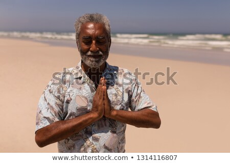 Stockfoto: Front View Of Senior Black Man With Hands Clasped Praying On Beach In The Sunshine