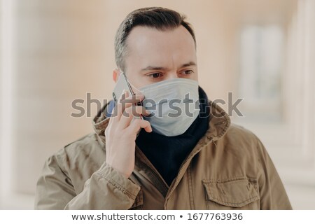 Stockfoto: Respiratory Protection Serious Man Has Telephone Talk Wears Medical Mask To Protect Against Virus