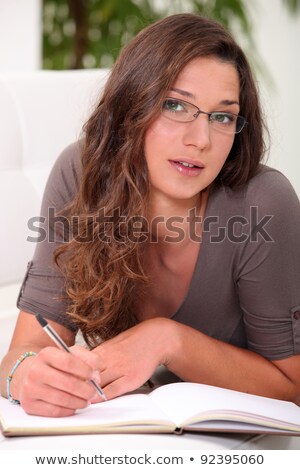 [[stock_photo]]: Intelligent Young Woman Writing In A Hardback Notebook