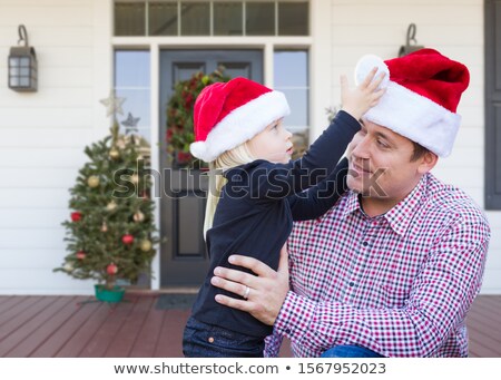 Stockfoto: Young Father And Daughter Wearing Santa Hats On Front Porch Of H