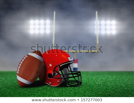 [[stock_photo]]: Football Ball And Helmet On Grass Under Spotlights