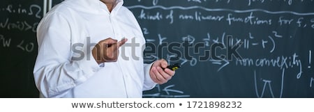 Foto d'archivio: Senior Male Teacher Teaching Mathematics Writing On The Blackboard