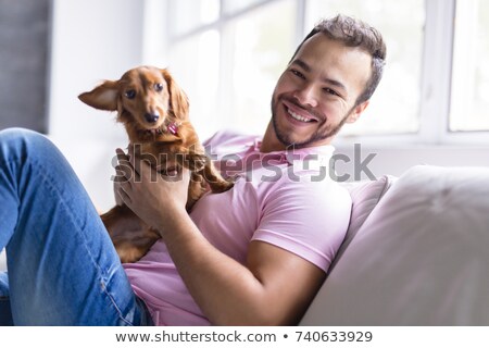 Foto stock: Young Mexican Man At Home Sitting On Couch With Dog