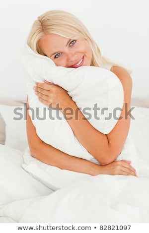 Stok fotoğraf: Happy Blonde Woman Hugging Her Pillow At Home In The Bedroom