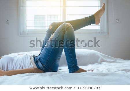 Stockfoto: Beautiful Woman Putting On Tight Jeans On A Bed