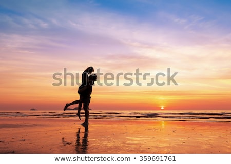 Foto stock: Na · pareja · besándose · al · amanecer · en · la · playa