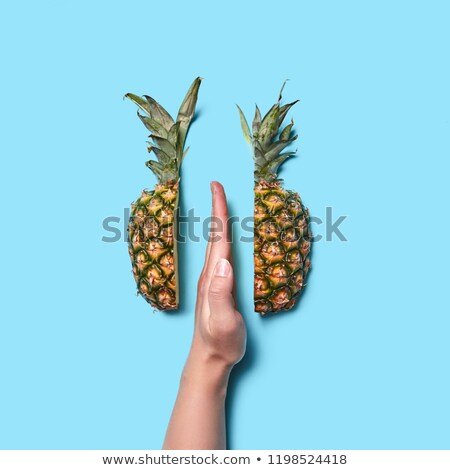 Foto stock: Creative Composition Of Pineapple Slices And A Female Hand Showing The Middle Finger On A Blue Backg