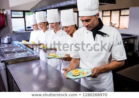 Stock fotó: Group Of Chefs Holding Plate Of Delecious Desserts In Kitchen At Hotel